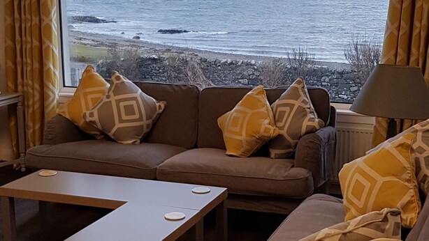 A living room with a large window overlooking a rocky coastline.