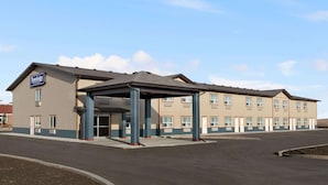 A hotel with a covered entrance, multiple rooms, and a parking lot. - Travelodge by Wyndham Pincher Creek (Pincher Creek)
