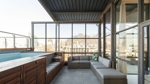 A rooftop terrace with a hot tub, seating area, and large windows offering city views. - Hillhouse Penthouse 7th Floor (Cape Town)