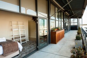 Een moderne hotelkamer met balkon, een houten bankje en uitzicht op de stad.