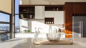 A modern kitchen with a large window, white cabinetry, and a stainless steel refrigerator. - Hillhouse Penthouse 7th Floor (Cape Town)