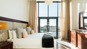 A spacious bedroom with a large bed, a nightstand, a dresser, and a television. - Hillhouse Penthouse 7th Floor (Cape Town)