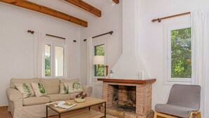 Ein Wohnzimmer mit einer Couch, einem Couchtisch, einem Kamin und einem Sessel.