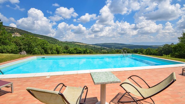 Piscina con vista su colline e cielo sereno.