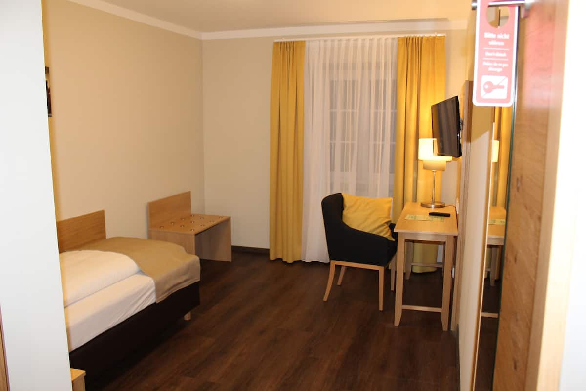 Ein Hotelzimmer mit einem Bett, einem Schreibtisch mit Stuhl, einer Lampe und einem Spiegel.