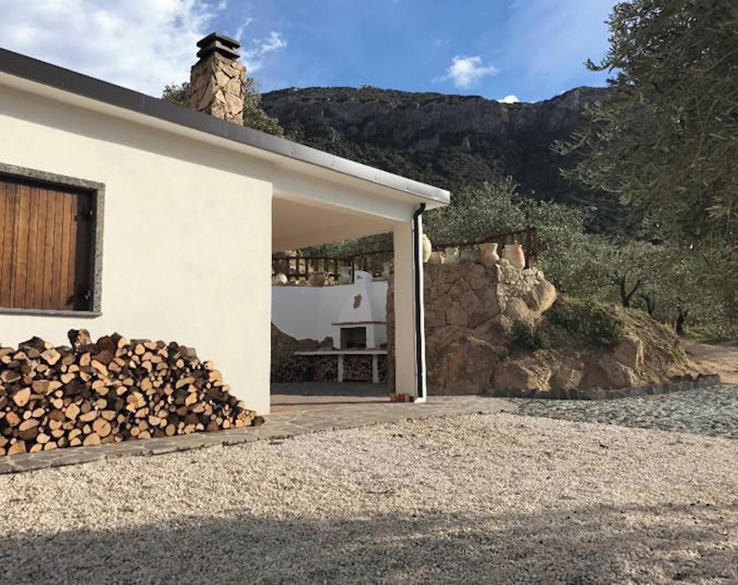 Ein modernes Haus mit einem Steinkamin, einer Schotterauffahrt und einem Holzstapel.