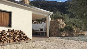 Ein modernes Haus mit einem Steinkamin, einer Schotterauffahrt und einem Holzstapel.