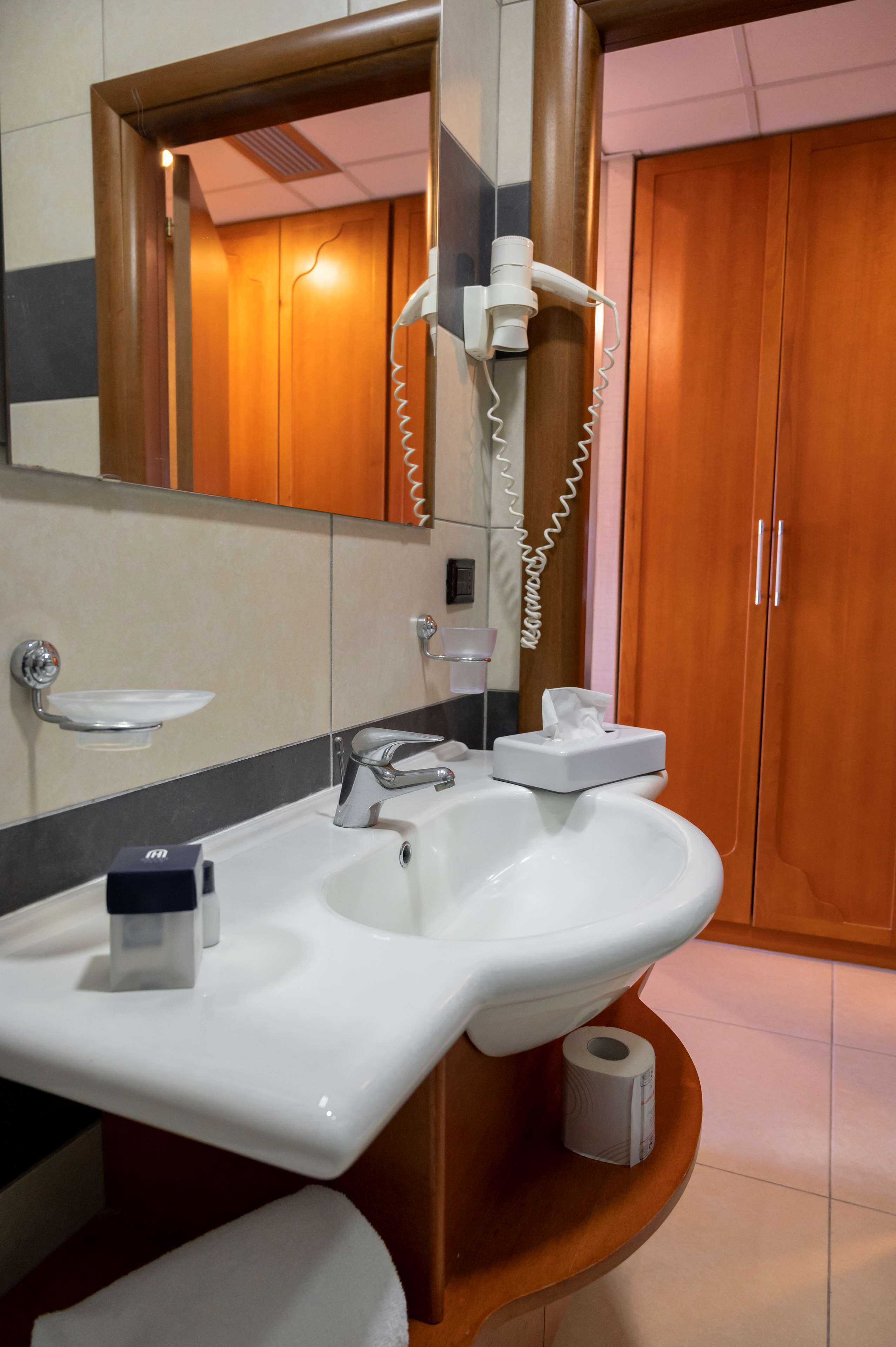 Un baño con lavamanos, espejo, toalla y retrete.