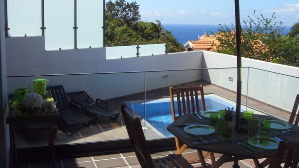Eine Dachterrasse mit Pool, Esstisch, Stühlen und Sonnenschirm.