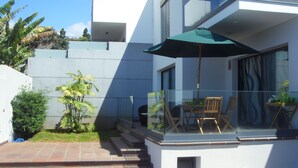 Eine moderne Außenpatio mit Glasgeländer, einem Pool und einem Essbereich mit Stühlen und Tisch.