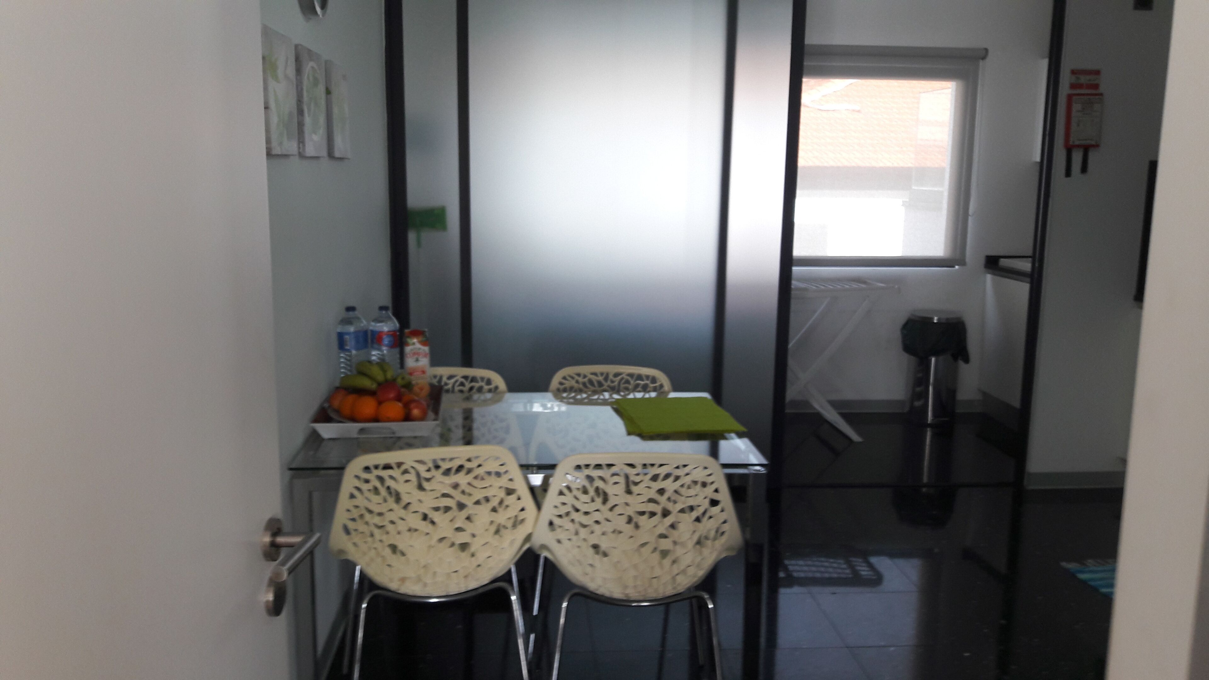 A dining area with a table and four chairs, a fruit bowl, and a bottle of water.