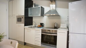 A modern kitchen with white cabinets, a stainless steel range hood, a microwave, an oven, and a refrigerator. - Singular Stays A. San Vicente IV (Valencia)