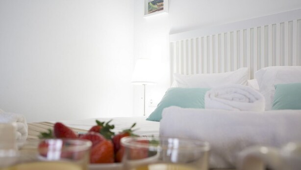 A hotel room with a neatly made bed, a bedside table with a lamp, and a breakfast tray with strawberries and a glass of orange juice. - Singular Stays A. San Vicente IV (Valencia)