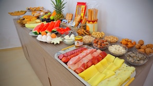 Un tavolo per buffet con diversi cibi tra cui frutta, formaggi, salumi e frutta secca.