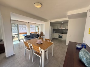 Una sala moderna con una mesa de comedor, sofá y zona de cocina.
