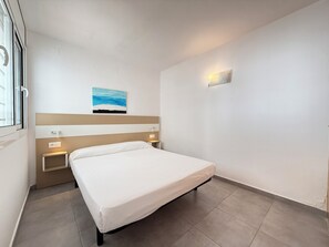 A hotel room with a bed, bedside tables, a painting, and a wall-mounted light. - Agi Las Acacias 2401 Apartamento for rent in Roses Girona. (Rosas / Roses)