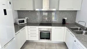 A compact kitchen with white cabinets, a built-in microwave, a stainless steel oven, and a dishwasher. - Agi Las Acacias 2401 Apartamento for rent in Roses Girona. (Rosas / Roses)
