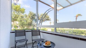 A balcony with two chairs, a small table, and a plate with bread and a cup.