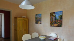 A dining area with a table, chairs, a cabinet, and two paintings on the wall.