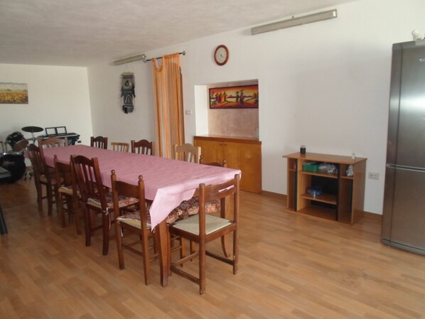 Ein Essbereich mit einem langen Holztisch, der mit einer rosa Tischdecke bedeckt ist, umgeben von Holzstühlen.