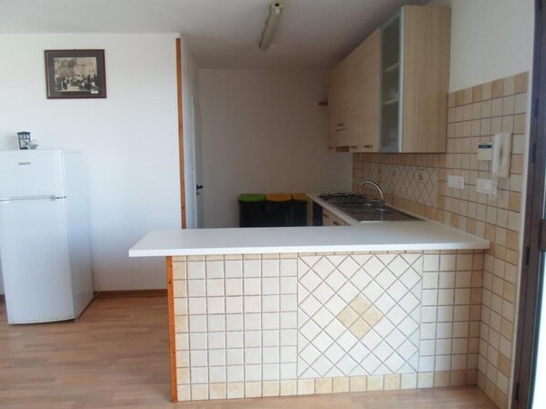 A compact kitchen with a white countertop, a stove, and wooden cabinets.