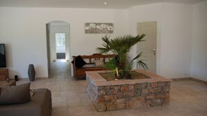 Un saló amb una jardiniera de pedra, un sofà, una banca de fusta i un quadre a la paret.
