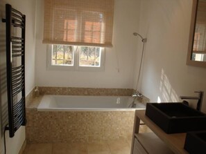 A bathroom with a bathtub, a window with blinds, a shower, and a towel rack. - Large 200 m² house with a private garden and swimming pool (Lorgues)