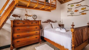 A bedroom with a wooden bed, a dresser, a staircase, and wall-mounted fish decorations. - Fisherman's House Azores (São Mateus) (Angra do Heroísmo)