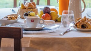 A breakfast table set with croissants, fruits, a jug of orange juice, and a coffee cup. - Agriturismo Buonasera (Bagnoregio)