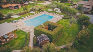 A pool surrounded by a well-maintained lawn, outdoor seating, and a rustic building structure. - Agriturismo Buonasera (Bagnoregio)