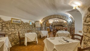 A restaurant with stone walls, white tablecloths, and a rustic interior. - Agriturismo Buonasera (Bagnoregio)