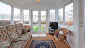 A room with a sofa, a television, and a chair. - Lovely foresters cottage, amazing Loch Ness views, private beach, pets welcome (Inverfarigaig,   Loch Ness)