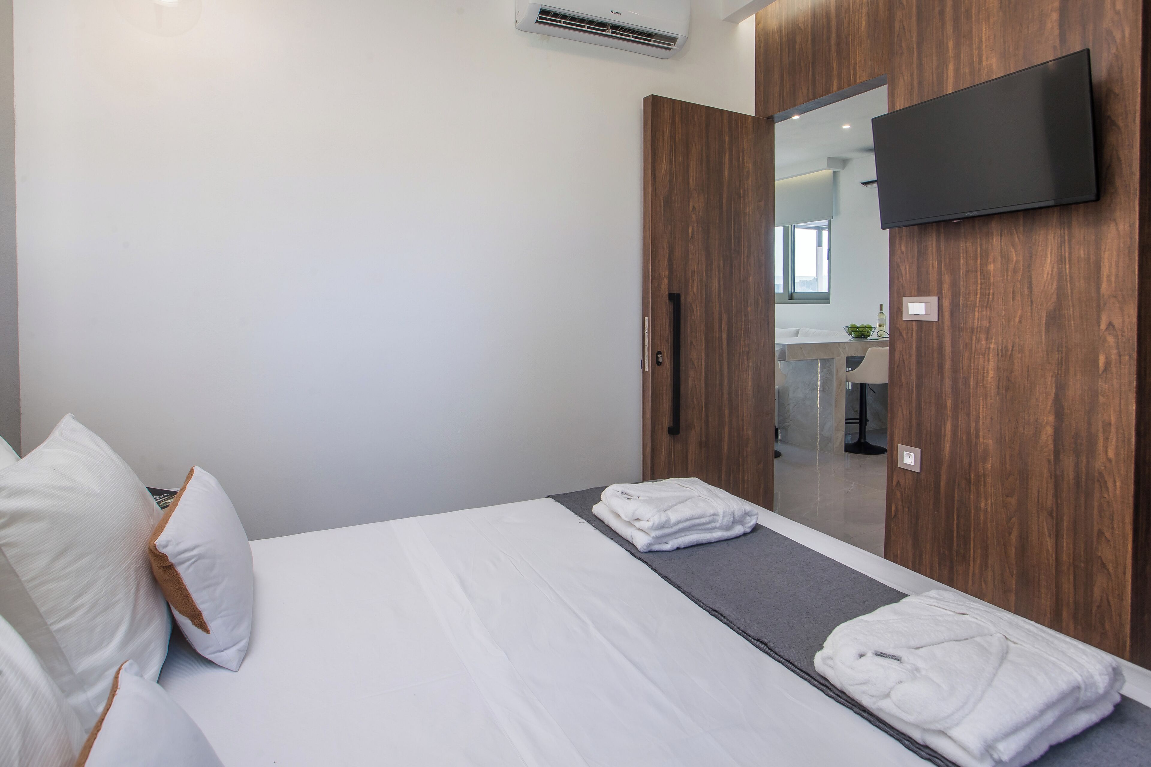 A hotel room with a bed, a TV mounted on the wall, and a mirror reflecting the bathroom.