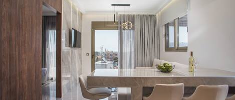 Una cocina moderna con encimera de mármol, zona de comedor con taburetes altos y vistas a la ciudad a través de amplios ventanales.