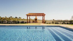 A swimming pool with a tiled deck and a wooden pergola with a barbecue grill. - Carmona - T2 Holiday Apartment by São Martinho do Porto beach By SCH (São Martinho do Porto)