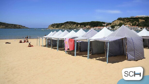 Beach umbrellas lined up on a sandy beach with a clear sky and a hilly landscape in the background. - Carmona - T2 Holiday Apartment by São Martinho do Porto beach By SCH (São Martinho do Porto)