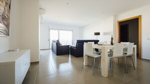A modern living room with a sofa, dining table, and chairs. - Carmona - T2 Holiday Apartment by São Martinho do Porto beach By SCH (São Martinho do Porto)