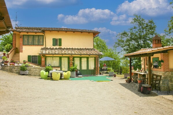 A two-story house with a patio area, outdoor seating, and a small garden.