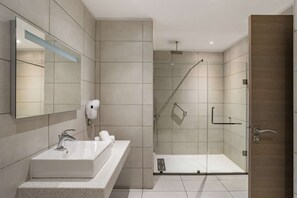 Un baño moderno con un lavamanos grande, espejo y zona de ducha.