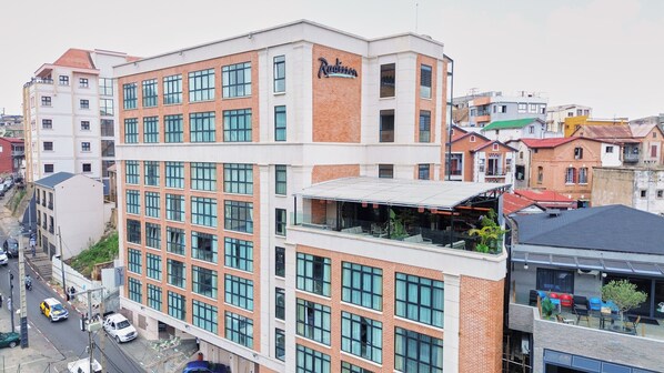 Un hotel de varios pisos con un llamativo letrero de 'Radisson', amplias ventanas y una terraza en la azotea.
