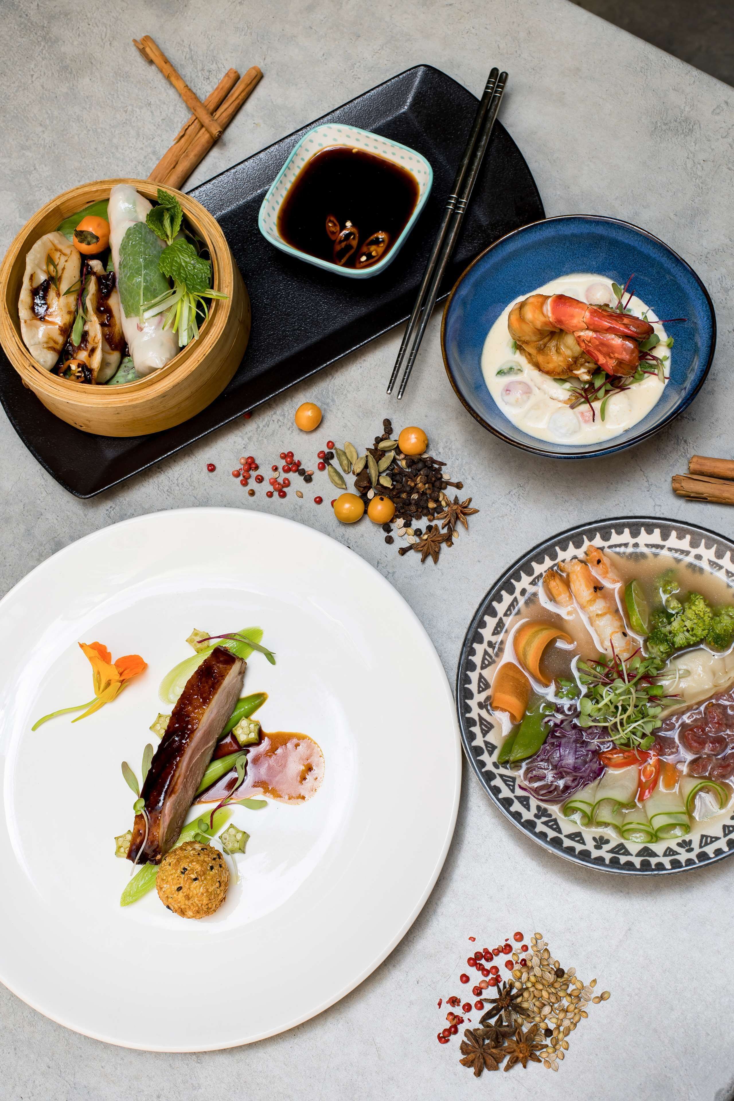 A table with various dishes, including seafood, vegetables, and a bowl of soup.