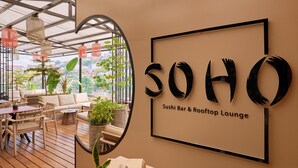 A sushi bar and rooftop lounge with a large sign, wooden furniture, potted plants, and a view of the city. - Radisson Serviced Apartments Antananarivo City Centre (Antananarivo)