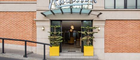 A hotel entrance with a brick facade, a glass canopy, and a sign reading "Radisson".