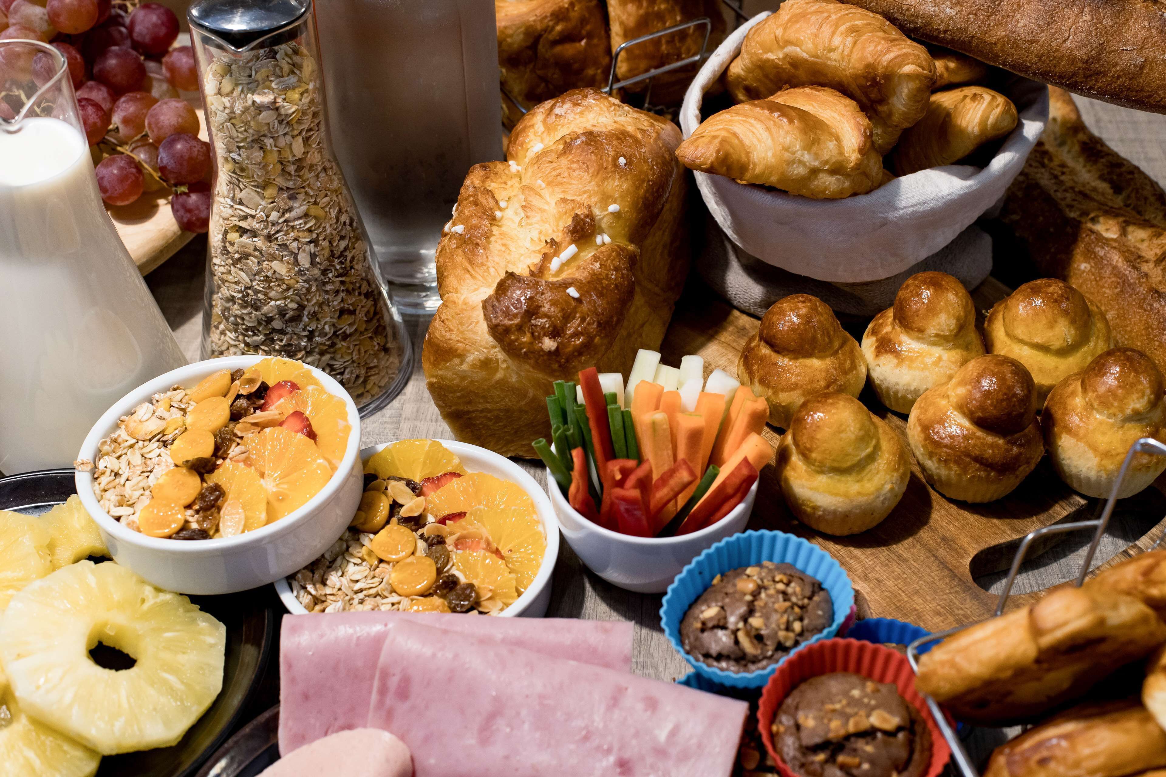 A breakfast buffet with various food items including pastries, fruits, and a milk pitcher.