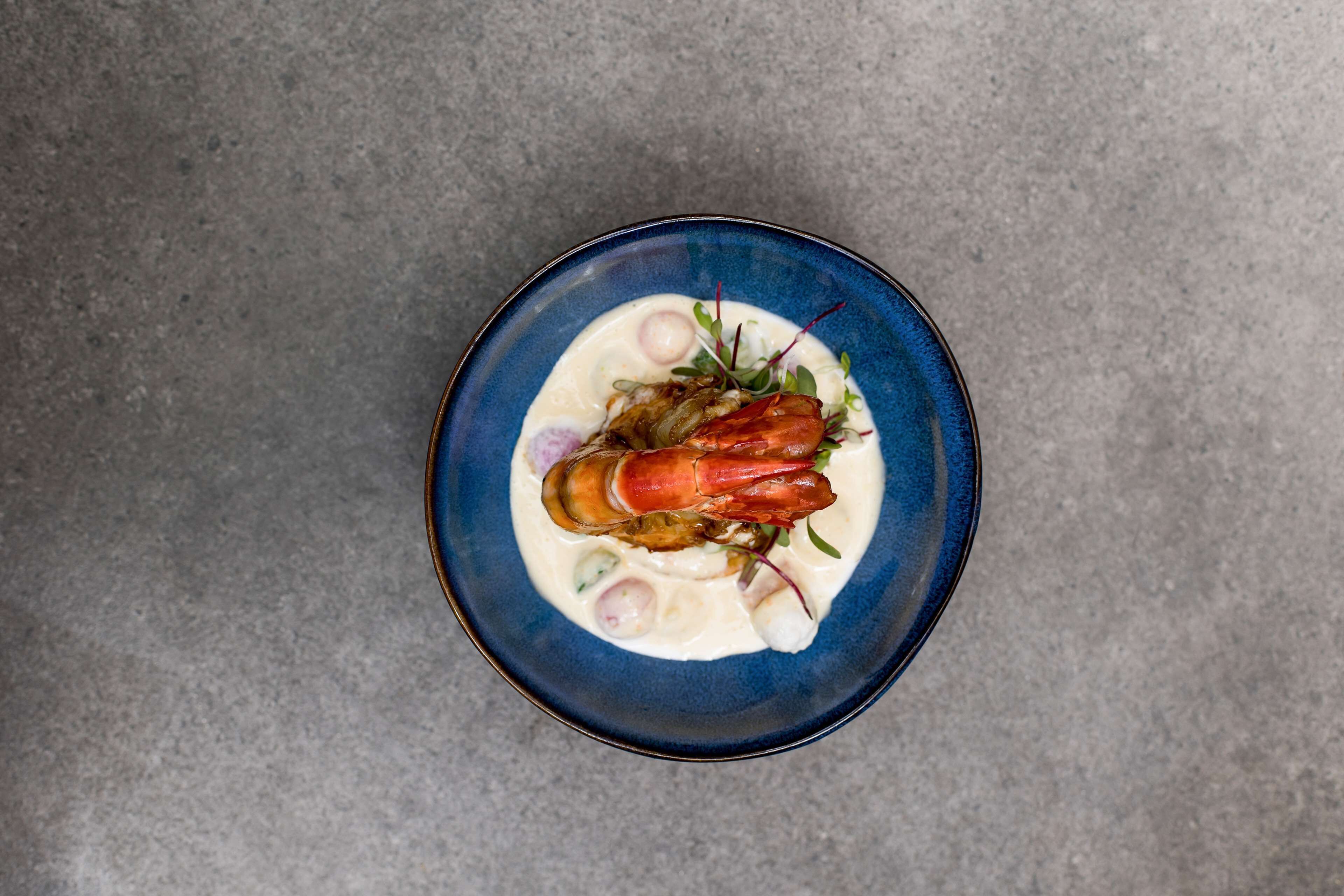 Un bol de nourriture avec un homard sur une assiette bleue.