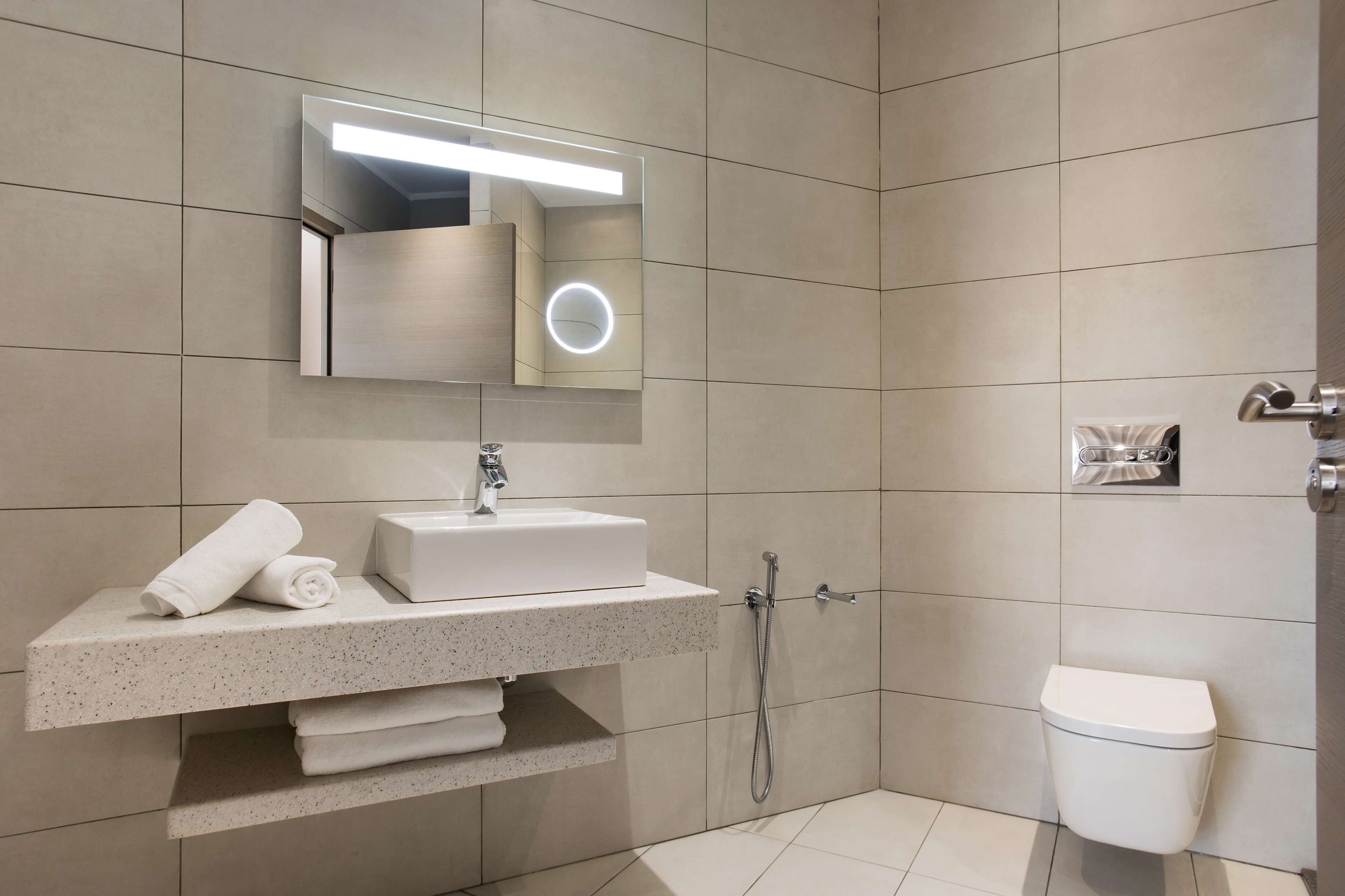 A modern bathroom with a built-in sink, mirror, and toilet.