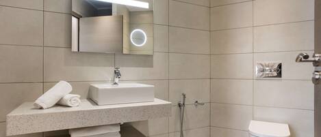 A modern bathroom with a built-in sink, mirror, and toilet.