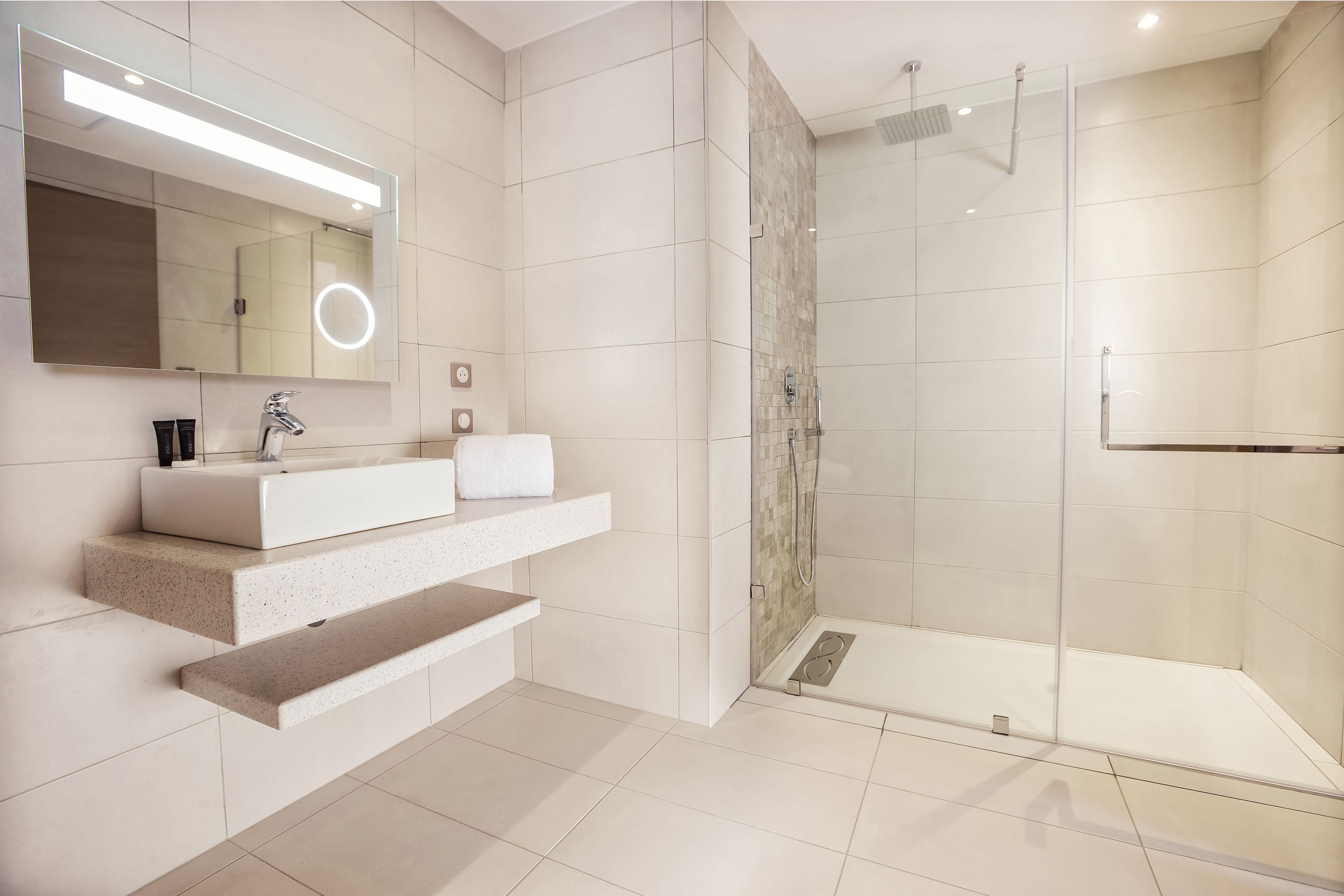 A modern bathroom with a large mirror, a sink, and a shower area.