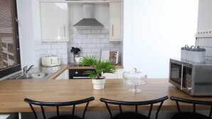 A modern kitchen with white cabinets, a stainless steel microwave, a toaster, and a potted plant on the counter.