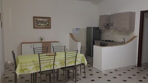 Een kleine keuken met een eethoek, een koelkast, een fornuis en een kast.